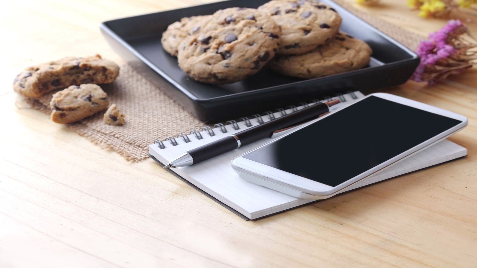 A kitchen table with a smartphone showing a simple Bitcoin wallet interface, a cup of tea, and a pair of reading glasses, representing everyday use
