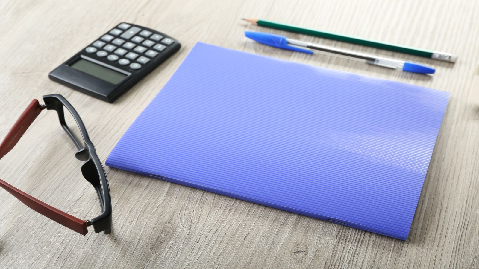 A well-organized desk with a ledger book open to columns of transaction records, a calculator, and a folder labeled with the current tax year