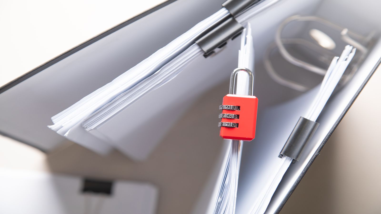 A padlock resting on a clean wooden surface beside a closed notebook, representing the protection of personal information