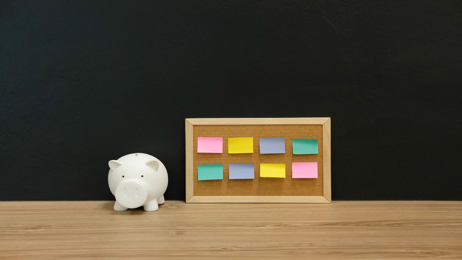 Five labeled index cards arranged neatly on a dark desk, each showing a different savings plan with handwritten figures